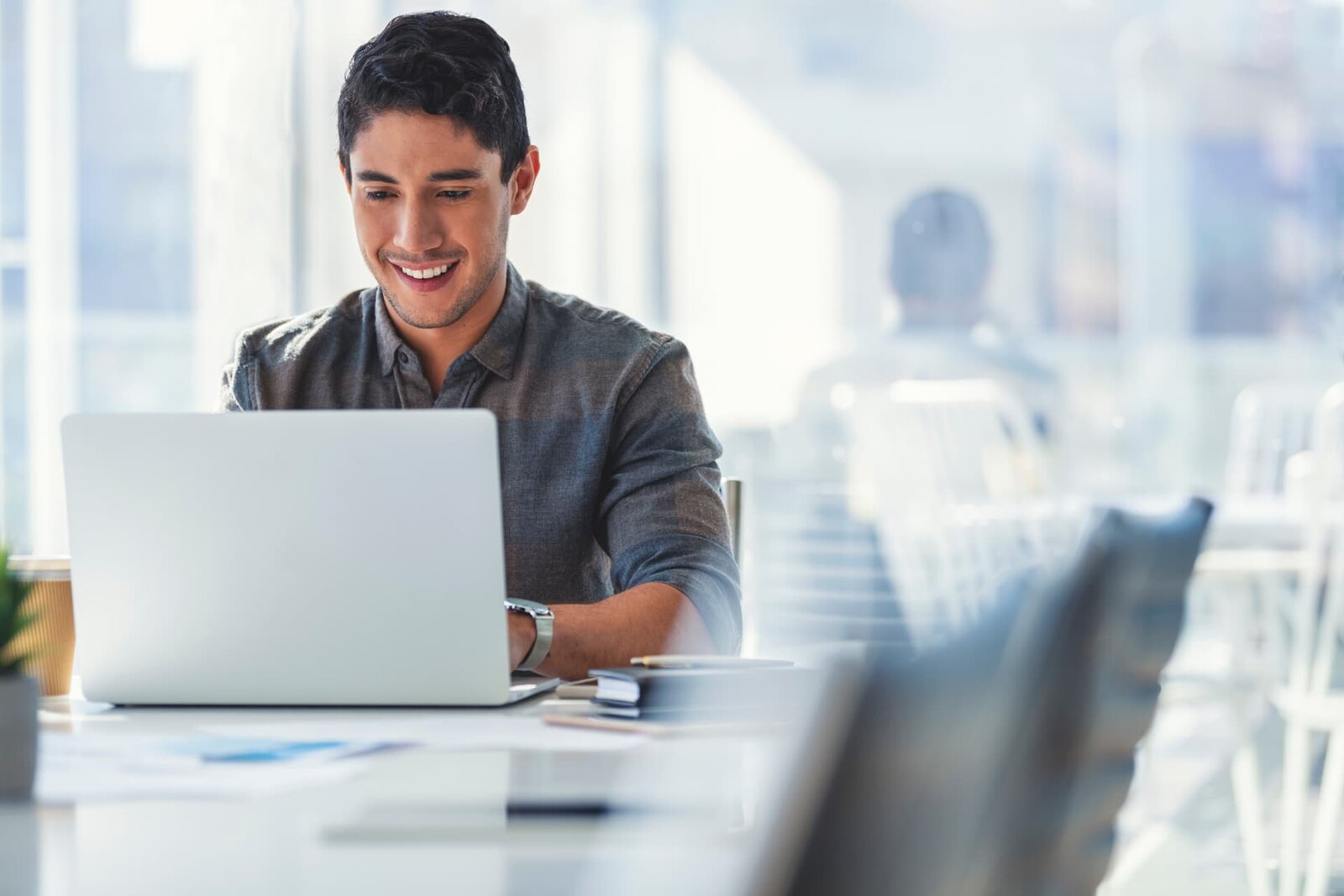 Man using a laptop in a bright shared workspace.