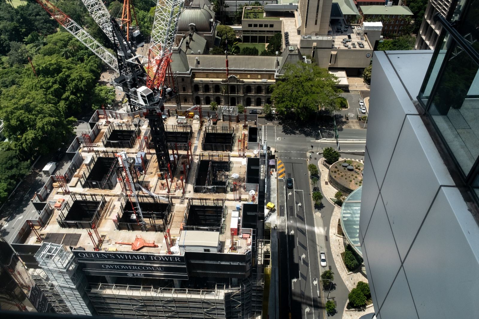 Aerial view of an inner-city high-rise construction site with tower cranes, exposed concrete cores and surrounding heritage and commercial buildings — illustrative of an off-the-plan development under construction.